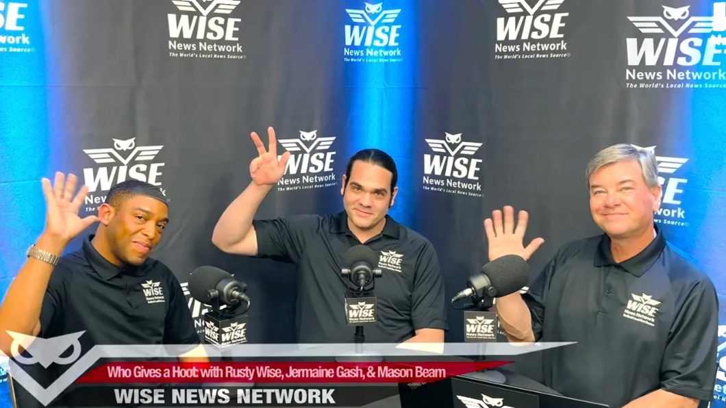 Three men are standing in front of a microphone.