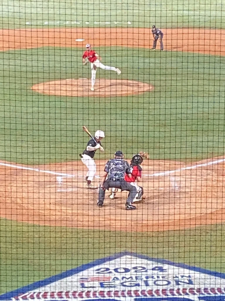 A baseball player about to swing at a ball flying through the air.