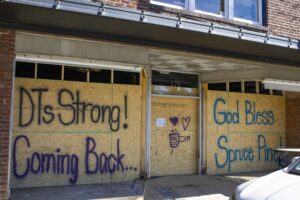 An image of DT's Blue Ridge Java being boarded up after flood damages with hopeful messages such as DT's Strong, Coming Back!, and God Bless Spruce Pine painted on it.