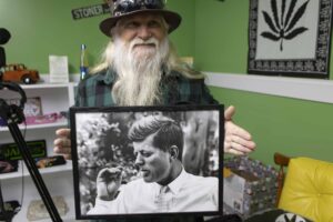 Jeff Williams holding a picture of John F Kennedy smoking.