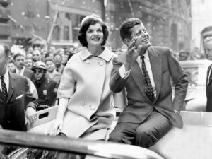 President John F Kennedy and his wife riding in a parade.