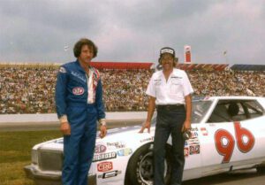 Will Cronkrite standing beside the number 96 car with its driver for NASCAR.