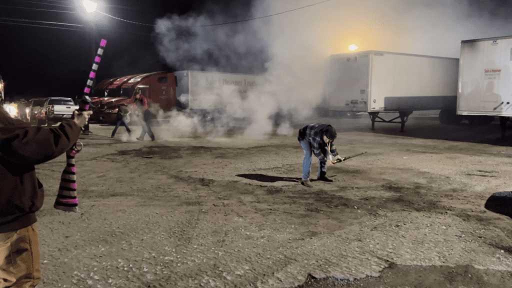 A man shooting a musket towards several transfer trucks. 