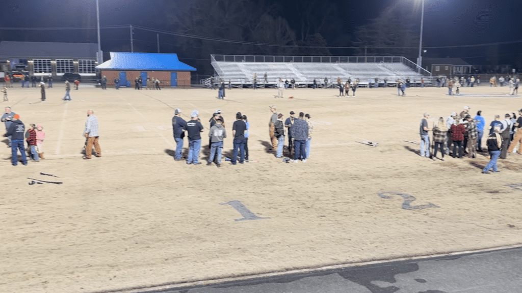 Several groups of people standing in a football stadium at night. 