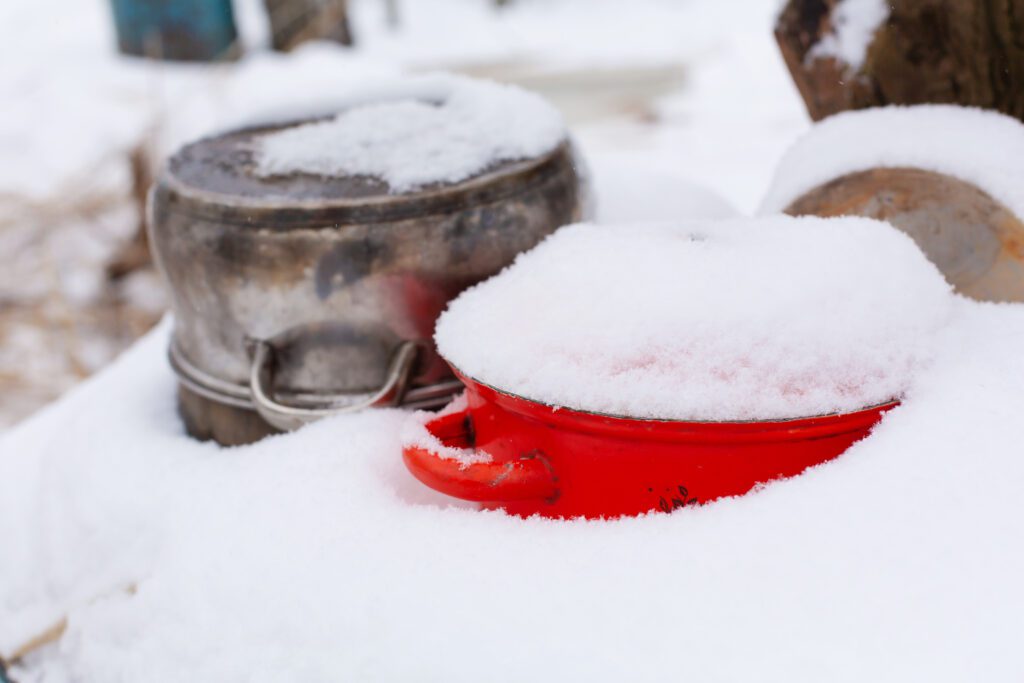 Old pots covered with snow on the street in winter.