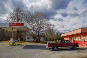 A bright orange convenience store with a gas pump station outside it surrounded by caution tape. The canopy of the pump station is leaning slightly.