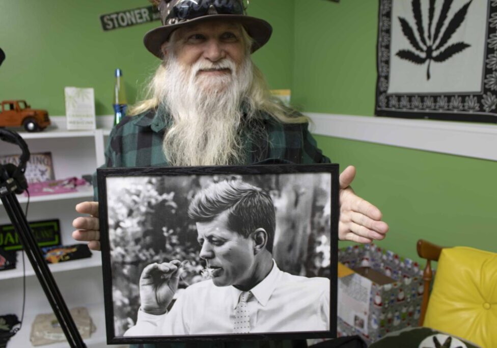 Jeff Williams holding a picture of John F Kennedy smoking.