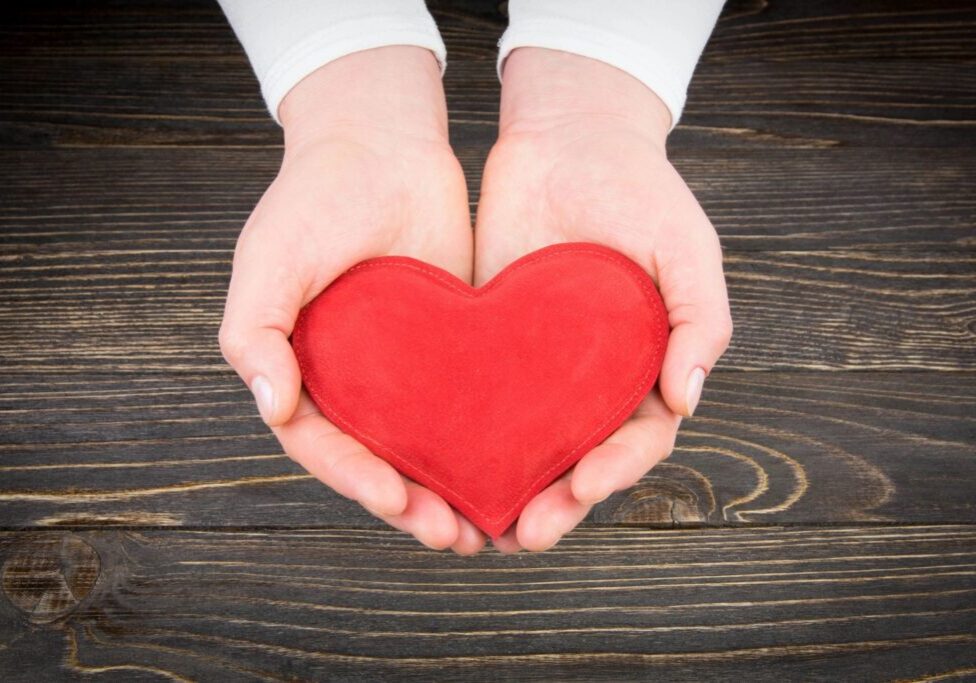 Hands holding a small fabric heart.