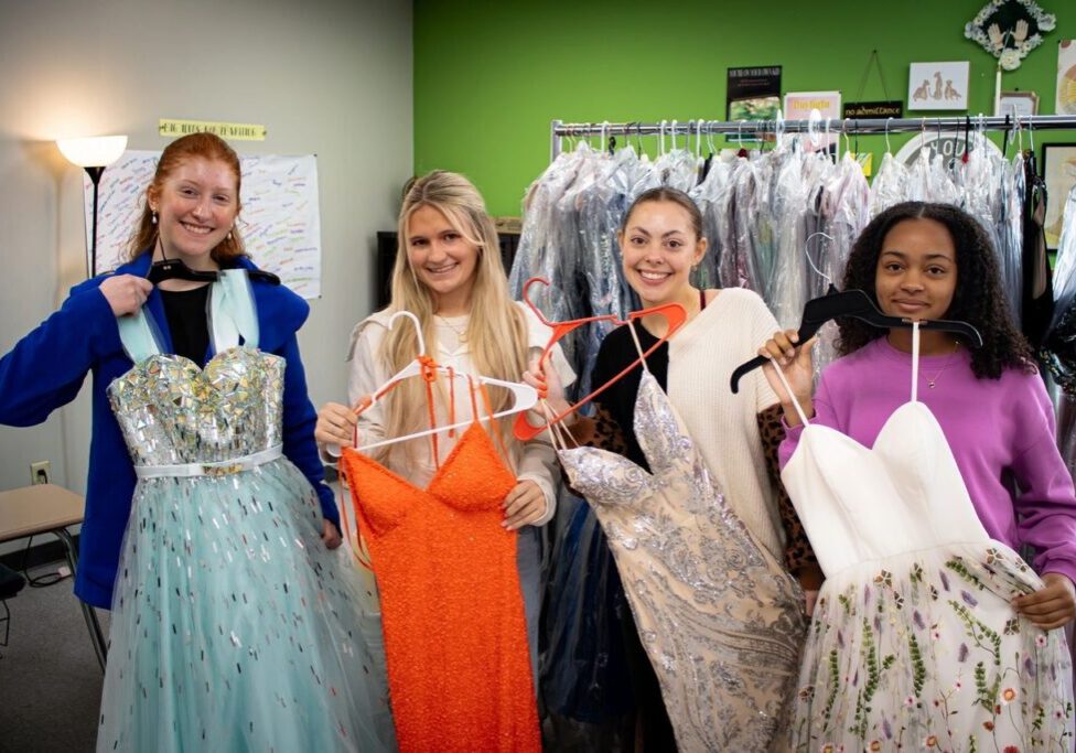 A group of people that are standing in front of some clothes.